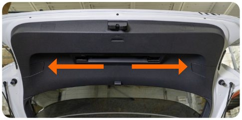 Inside of the open rear hatch of a VW Golf with arrows pointing left and right to the two tail light access covers