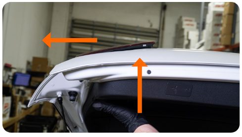 Arrows showing the inner tail light being pushed up and then outward off the hatch of a VW Golf