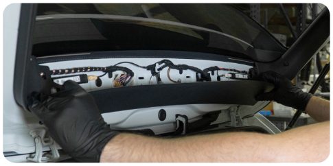 Hands pulling the middle trim piece away from the rear window of a VW Golf hatch