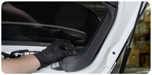Gloved hands removing a side trim piece from the hatch of a VW Golf