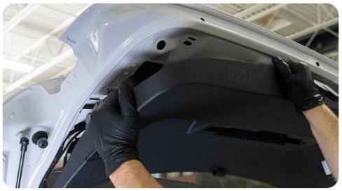 Hands pulling the hatch trim panel down and away from the hatch of a VW Golf