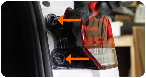 Two arrows pointing to the T25 bolts behind the outer tail light of a VW Golf