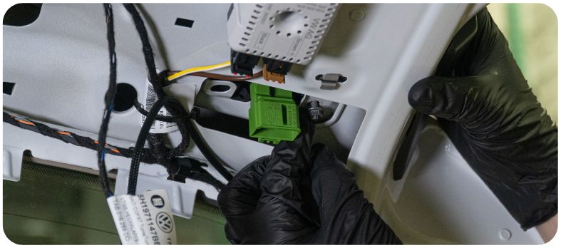 Gloved hands seating the new inner tail light on the hatch of a VW Golf with the connector visible through the opening